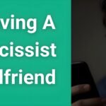 Man looking contemplative while holding phone, representing the difficulty of leaving a narcissist girlfriend